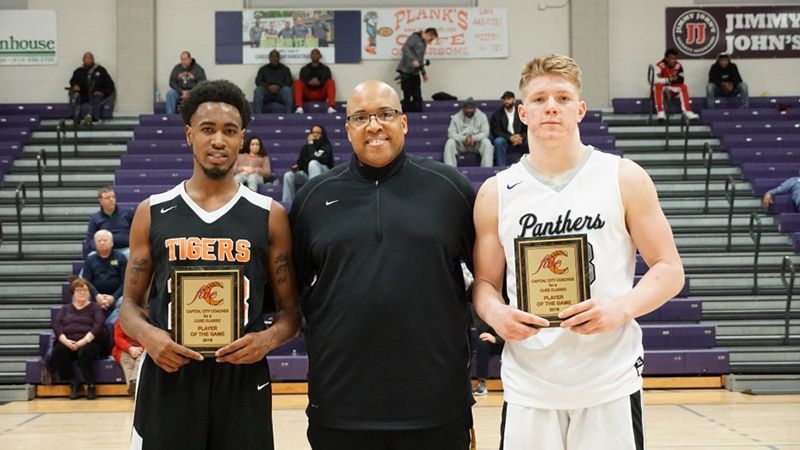 Two basketball players and a coach are posing for a picture