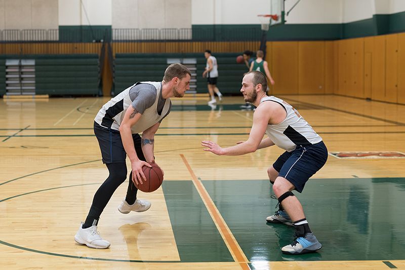 Two men are playing basketball on a court.