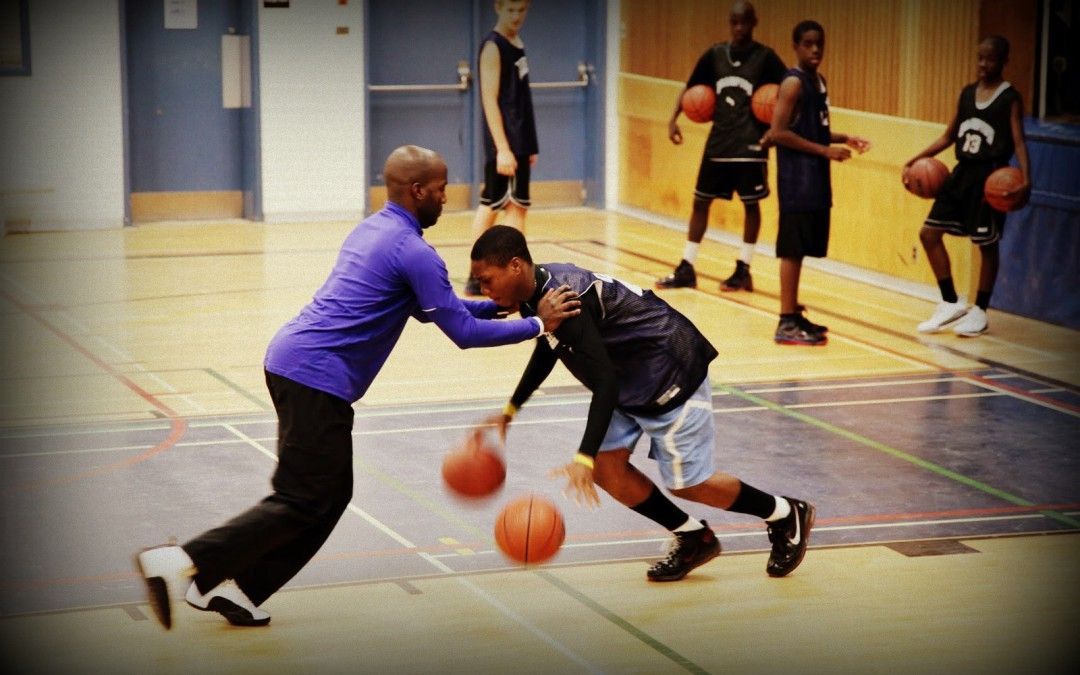 A man in a purple shirt is playing basketball with another man