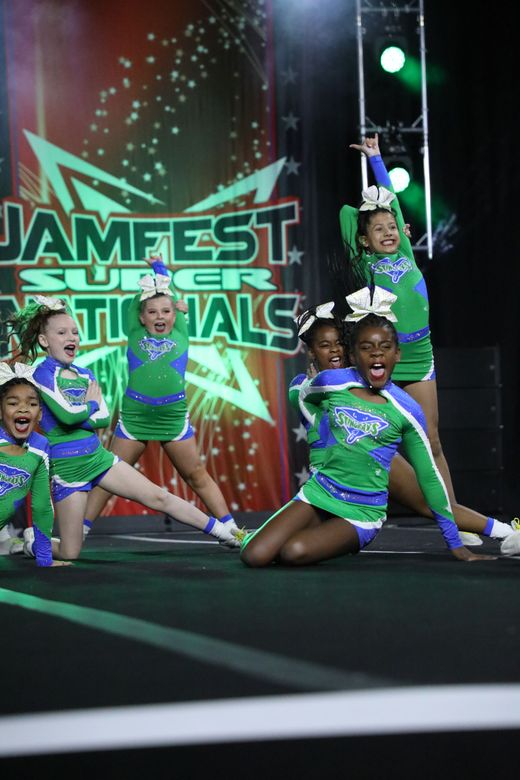 A group of cheerleaders are posing for a picture on a stage.