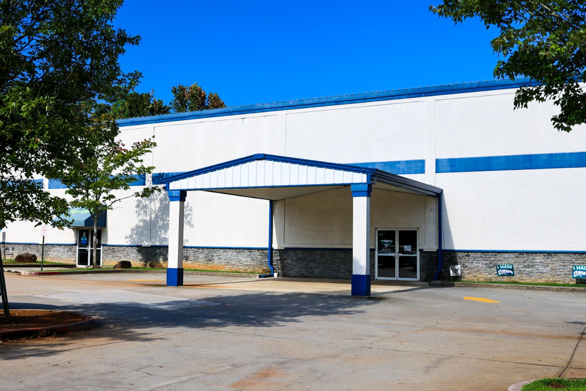 A white and blue building with a blue awning over the entrance