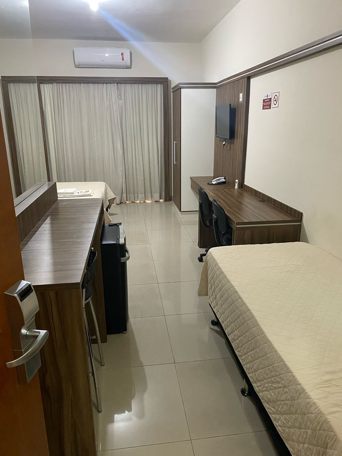 Um quarto de hotel com duas camas, uma escrivaninha e uma televisão.