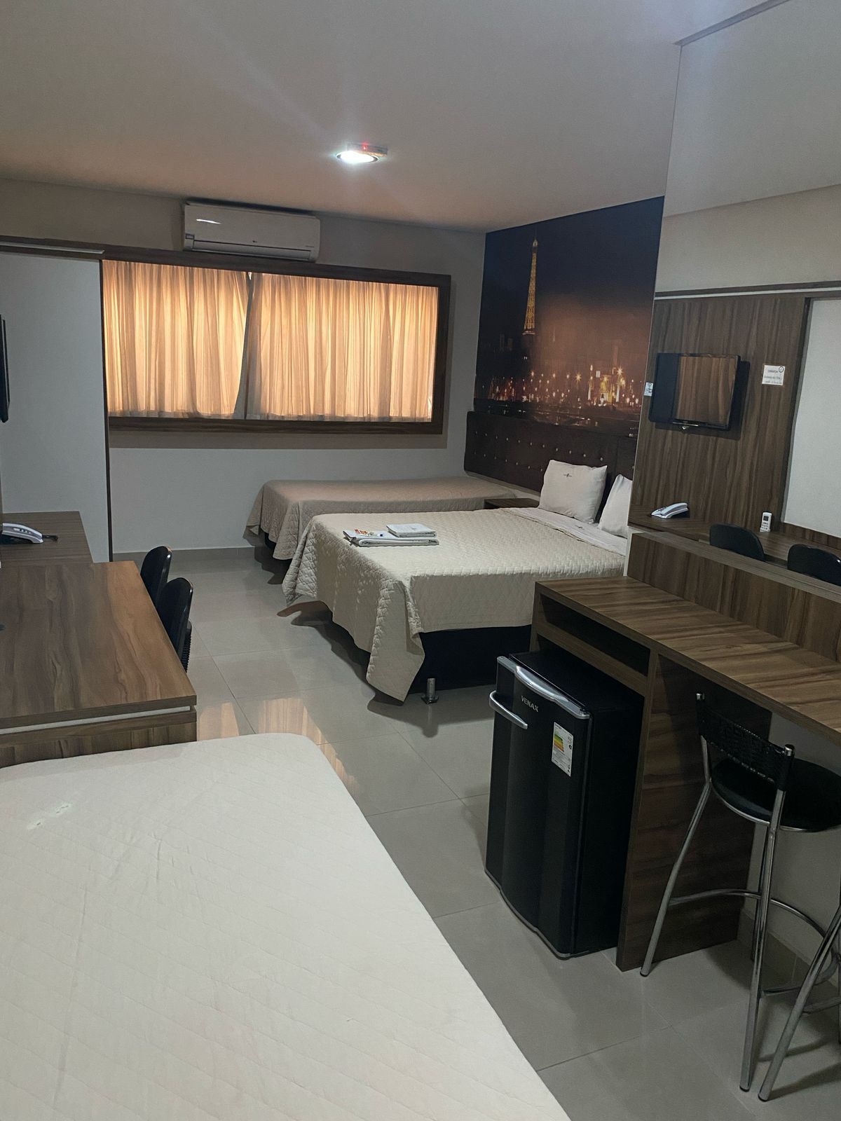 Um quarto de hotel com três camas e uma escrivaninha.