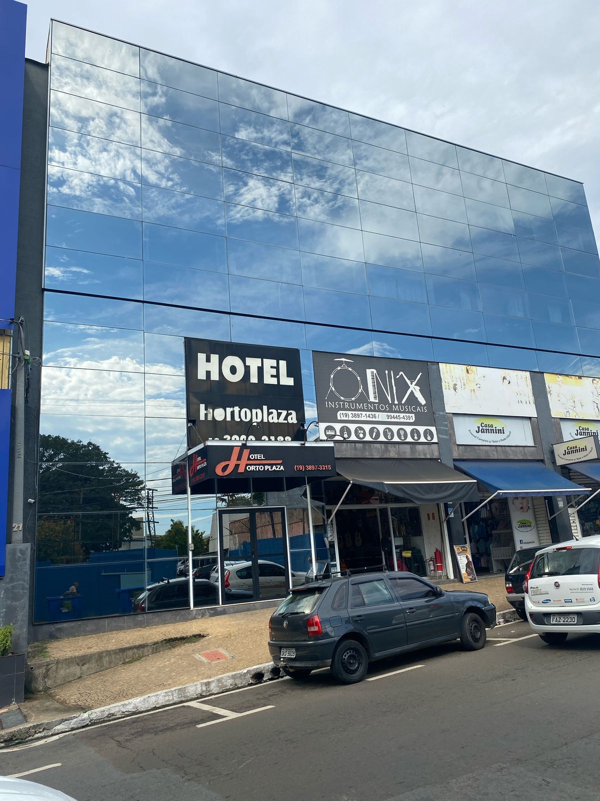 Um carro está estacionado em frente a um prédio que diz hotel