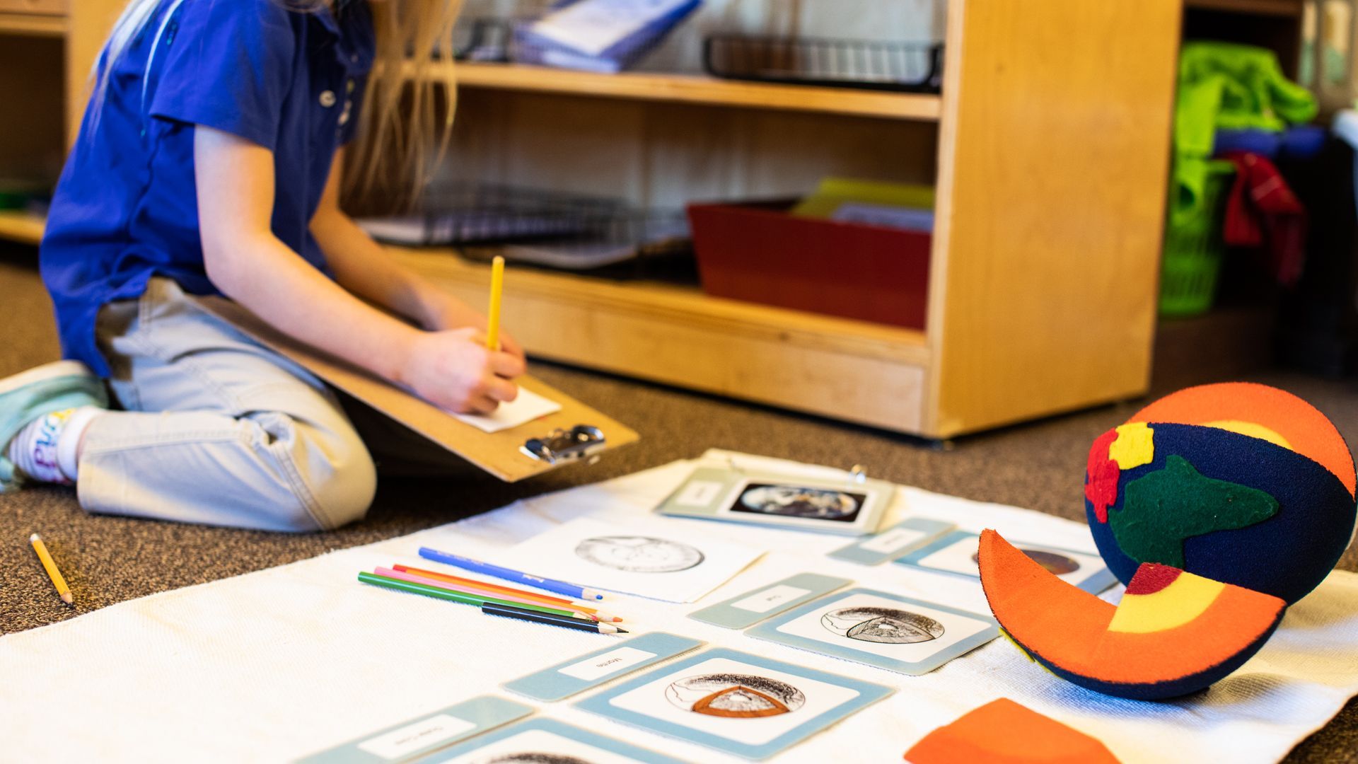Child working on floor with Montessori cosmic education materials in a classroom