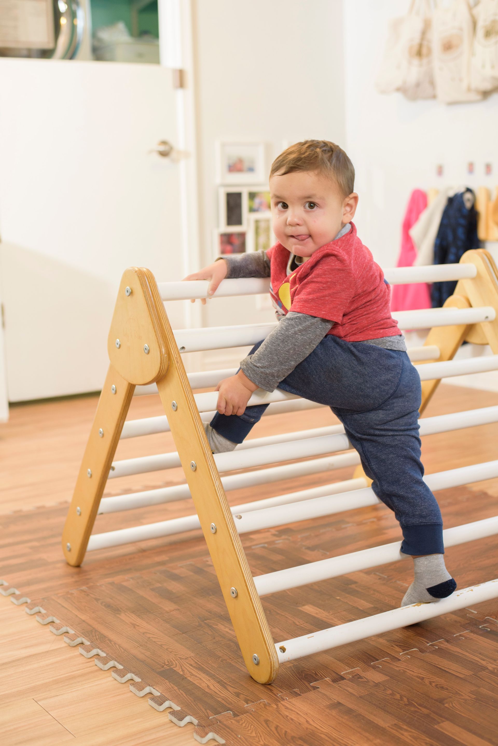 Child climbing on a wooden indoor play ladder in a bright room