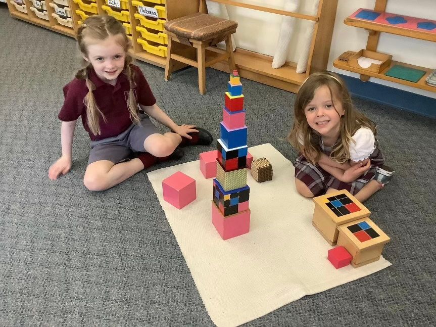 Children sitting on a classroom rug playing with colorful block towers and wooden blocks