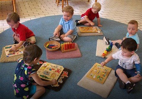 A group of children are playing with montessori material on the floor