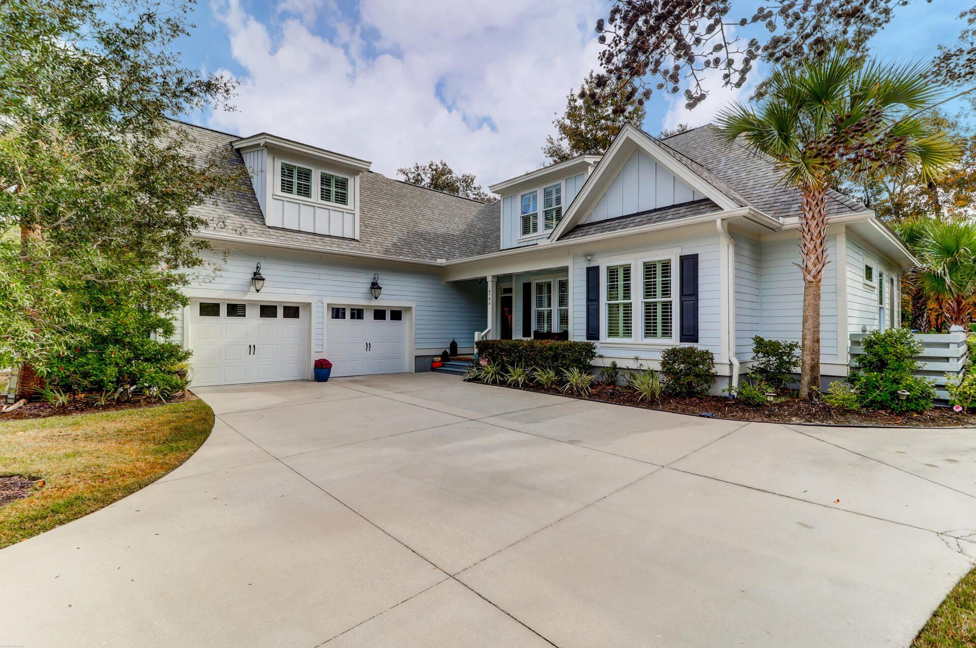 White suburban house with two-car garage, curved driveway, and landscaped front yard
