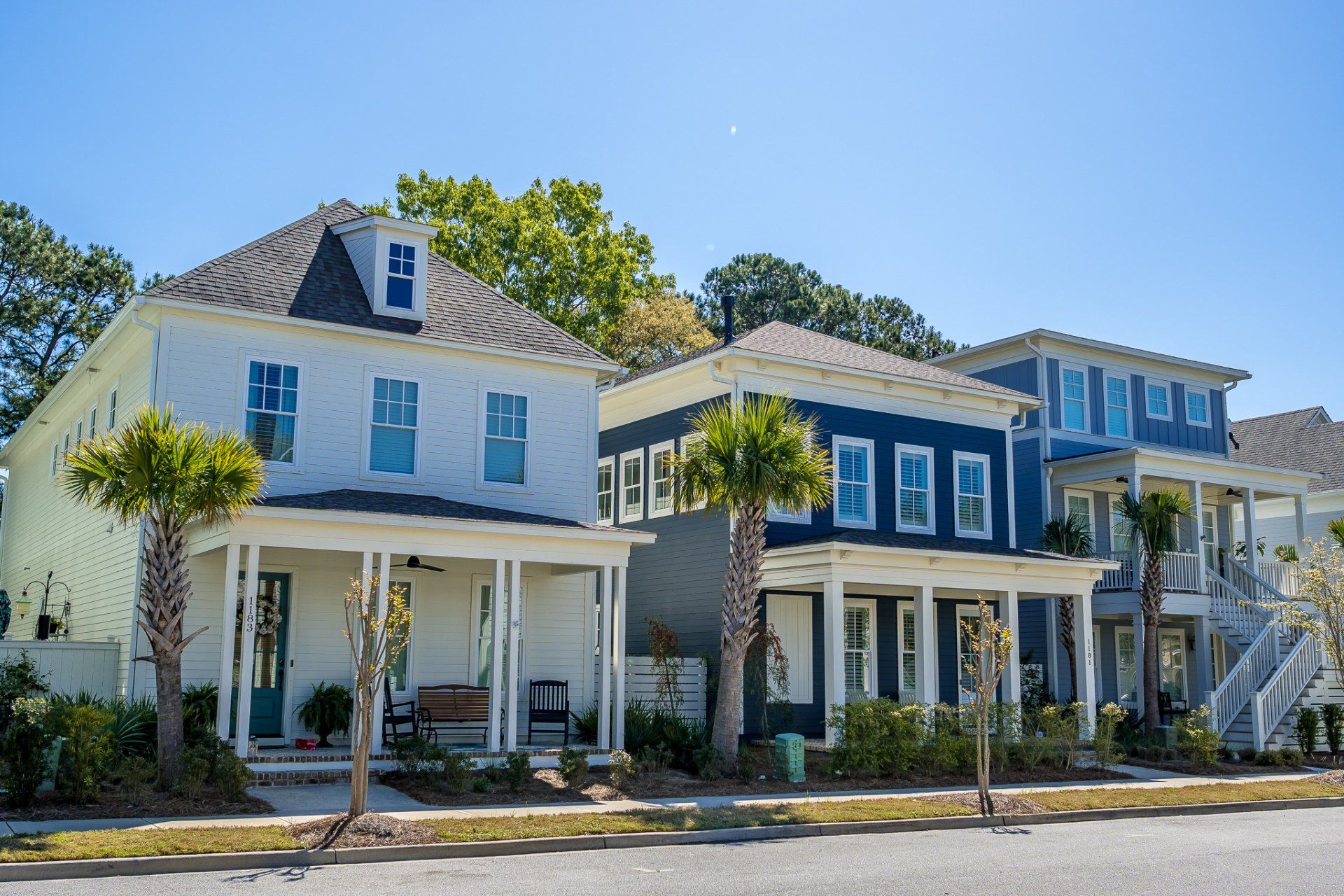 Row of blue and white coastal houses with porches along a sunny street