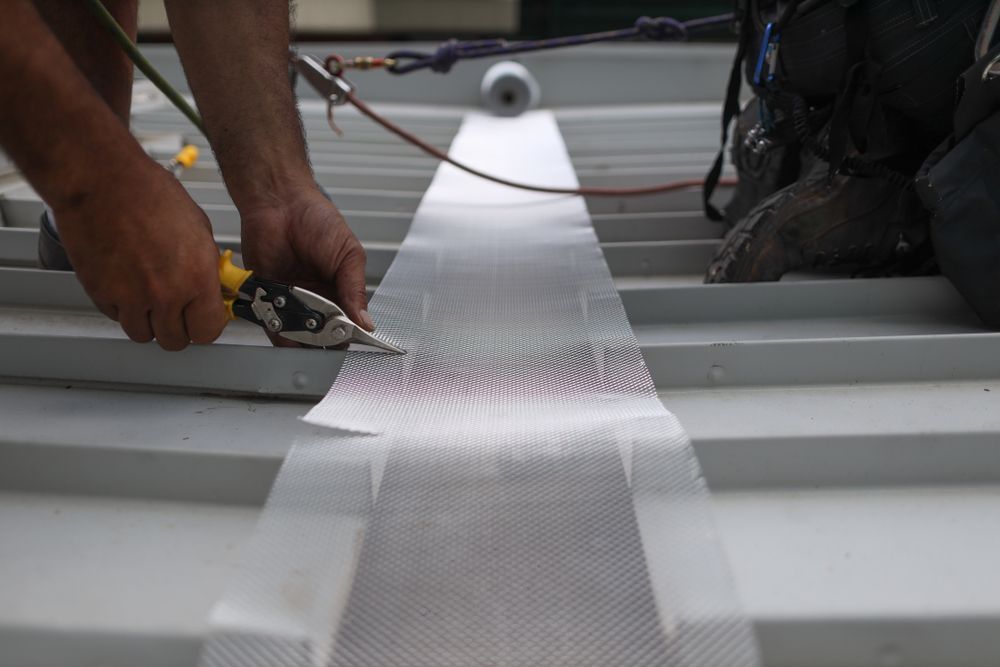A Man is Working on a Roof With a Pair of Pliers — Northern Rivers Metal Roofing PTY LTD In Ewingsdale, NSW