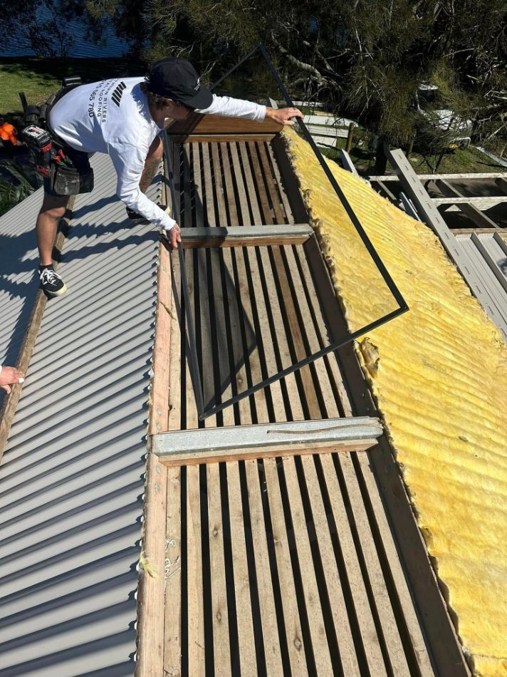 A Man is Working on the Roof of a Building — Northern Rivers Metal Roofing PTY LTD In Pottsville, NSW