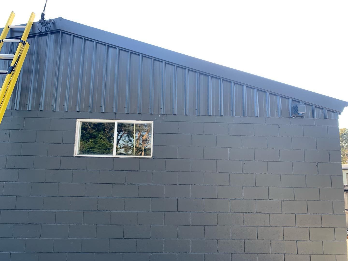 A Ladder is Hanging From the Side of a Building — Northern Rivers Metal Roofing PTY LTD In Mullumbimby, NSW