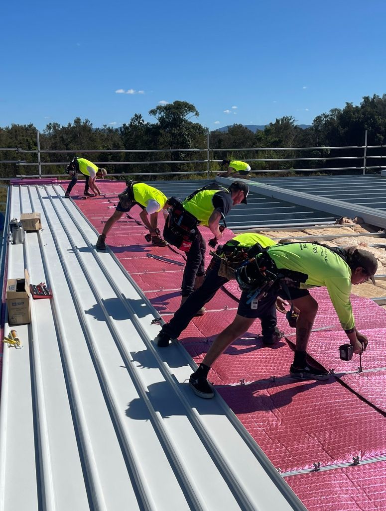 A Group of Construction Workers Are Working on a Roof — Northern Rivers Metal Roofing PTY LTD In Ewingsdale, NSW