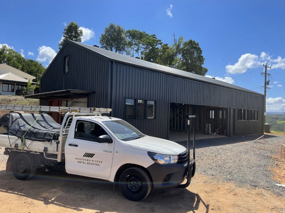 A White Truck is Parked in Front of a Large Building — Northern Rivers Metal Roofing PTY LTD In Ewingsdale, NSW