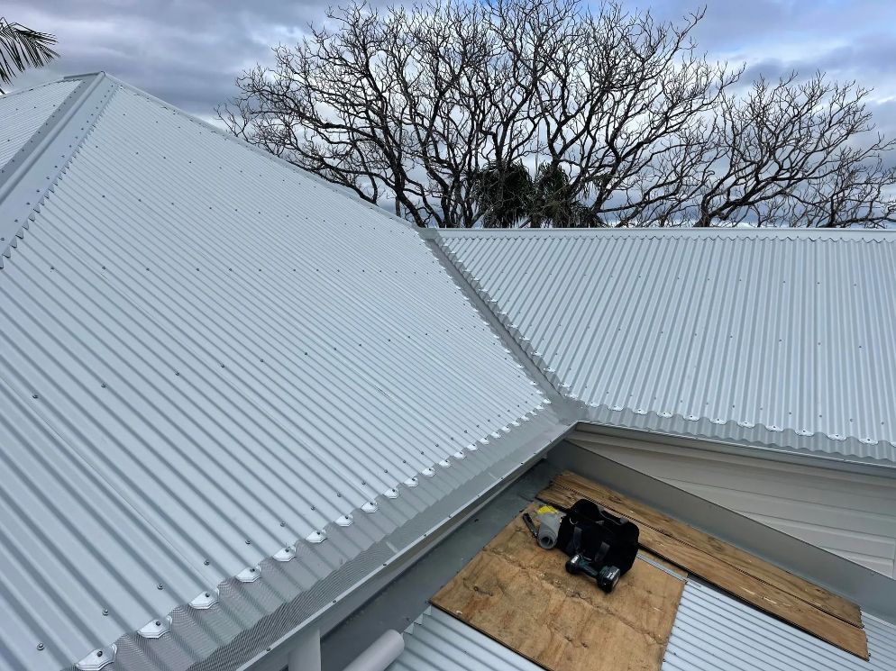 A White Corrugated Metal Roof is Being Installed on a House — Northern Rivers Metal Roofing PTY LTD In Murwillumbah, NSW
