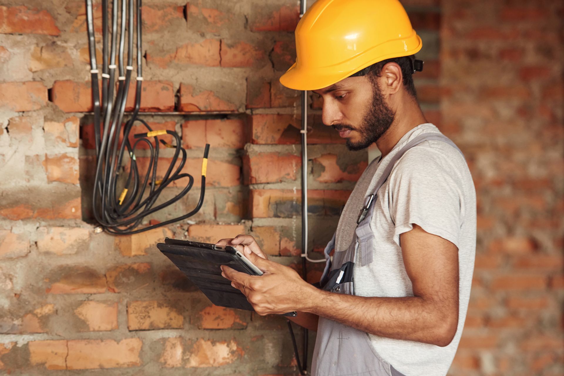 a man wearing a hard hat is looking at a clipboard .