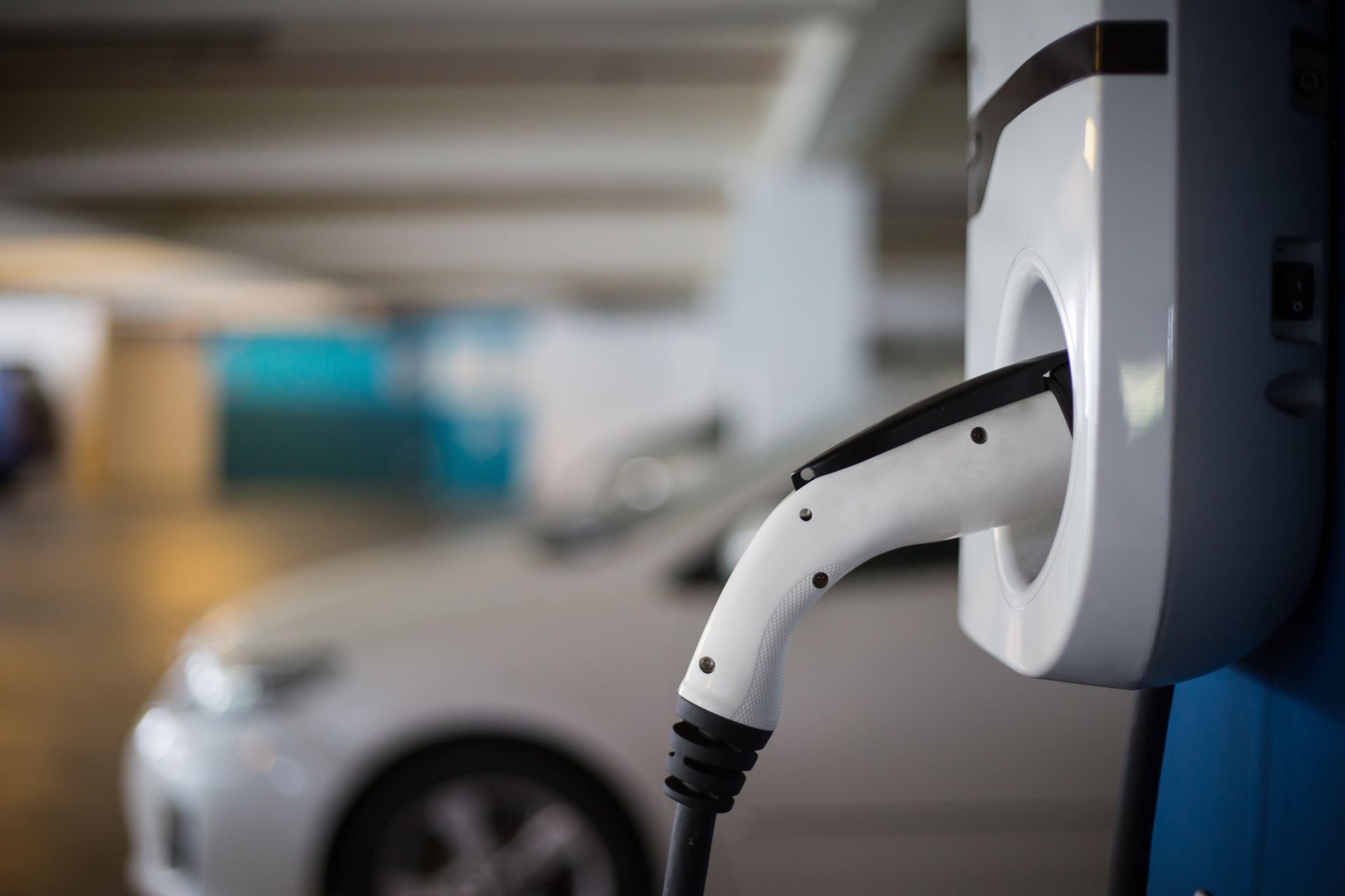 An electric car is being charged at a charging station in a parking garage.