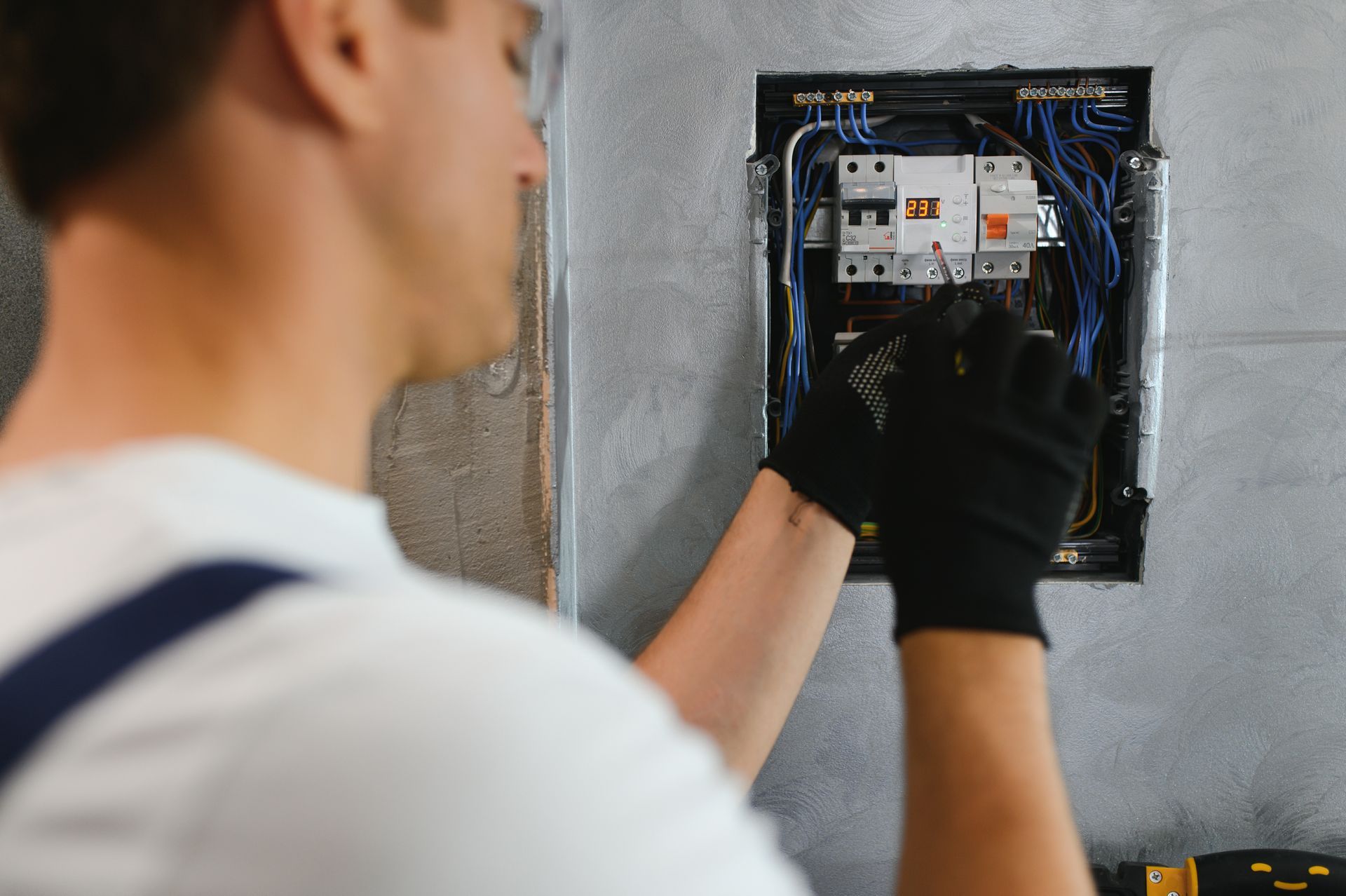 a man is working on an electrical box on a wall .