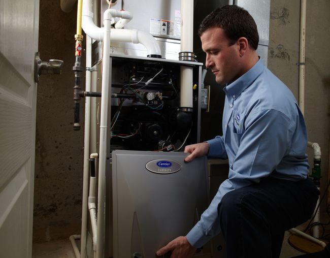 a man is holding two gauges in front of an air conditioner .