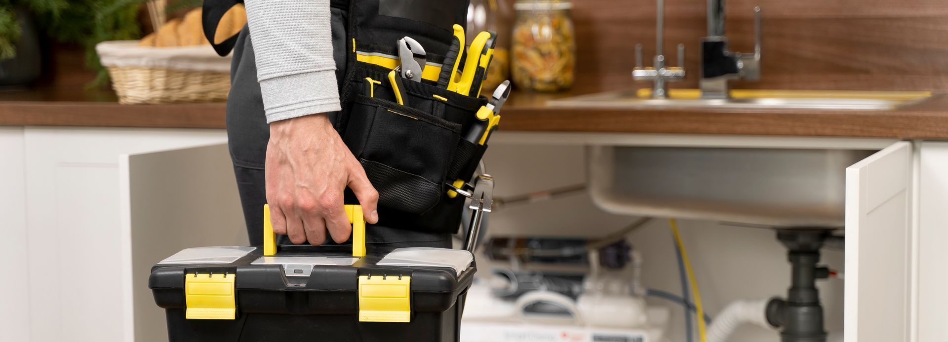 Person holding a black-and-yellow tool bag in a workshop or garage