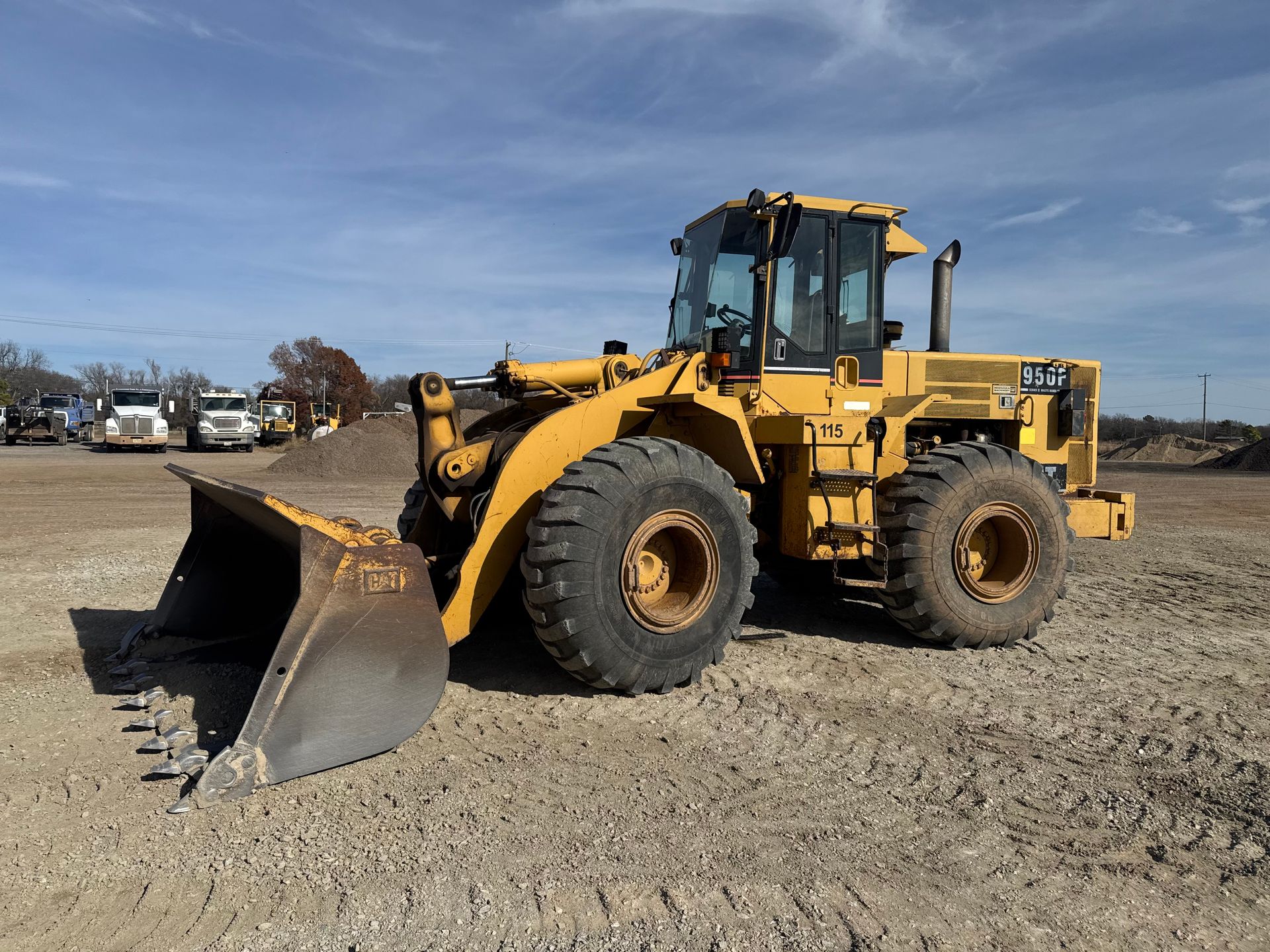 Yellow front loader parked on gravel lot under a blue sky