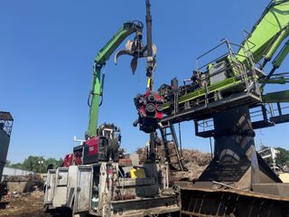 Construction machinery demolishing a large structure, with green excavators and a loader amid rubble