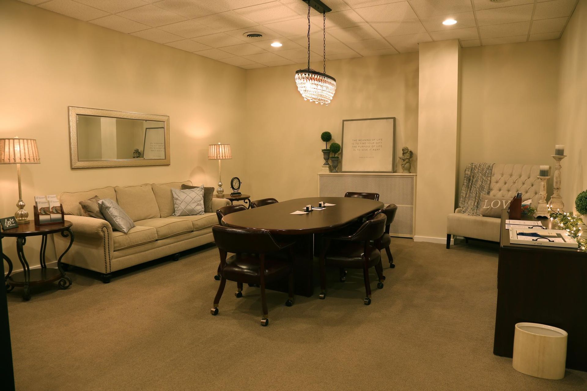 Office waiting room with sofas, chairs, coffee table, and soft beige lighting