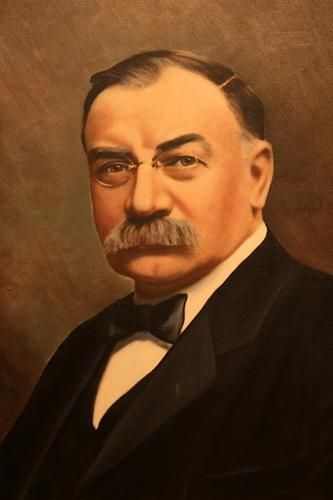 Formal painted portrait of a stern man in a dark suit, bow tie, and mustache on a warm brown background
