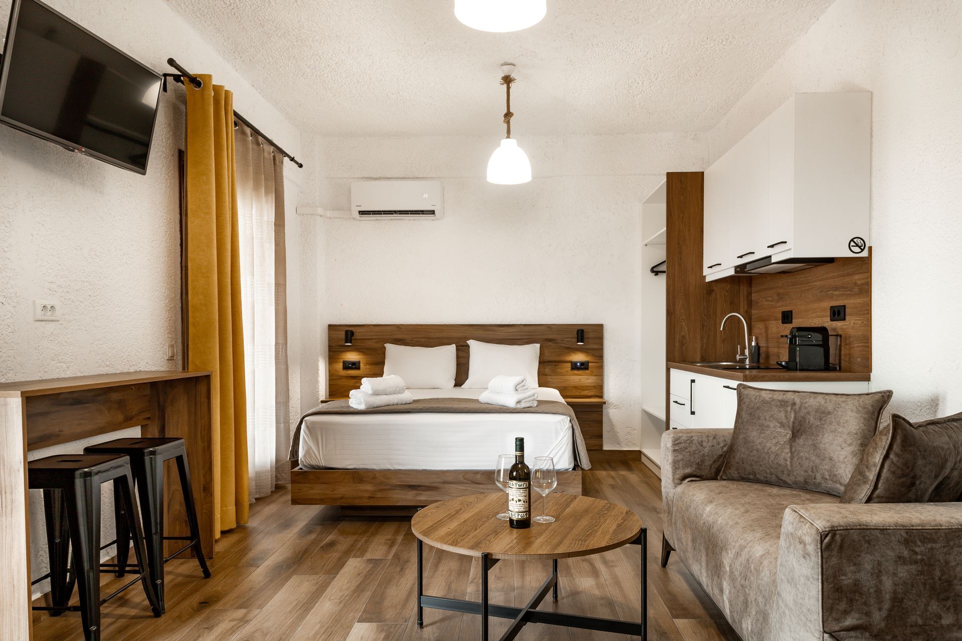 Modern studio apartment with bed, sofa, kitchenette, and wooden coffee table
