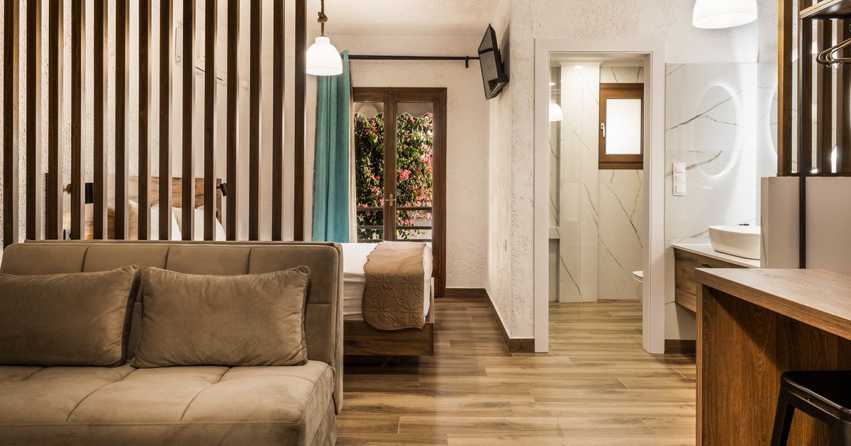 Balcony with climbing plants, wooden trellis, and window with dark blinds on a beige wall