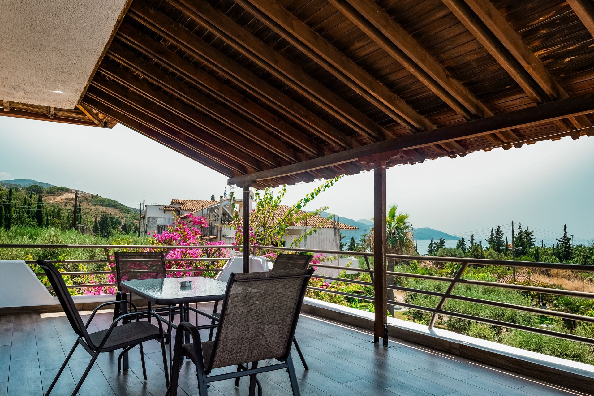 Covered patio with table and chairs overlooking a scenic green valley and mountains