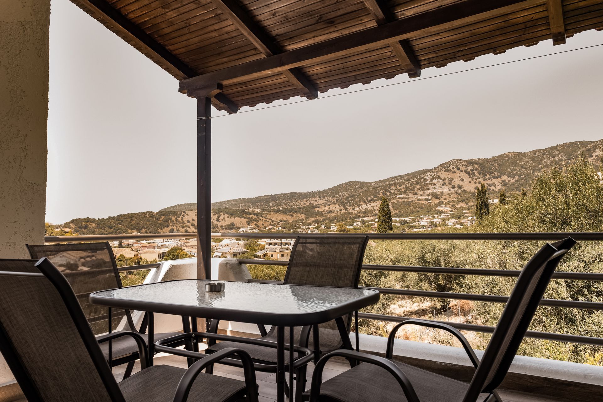 Patio with table and chairs overlooking a mountainous landscape under a wooden roof
