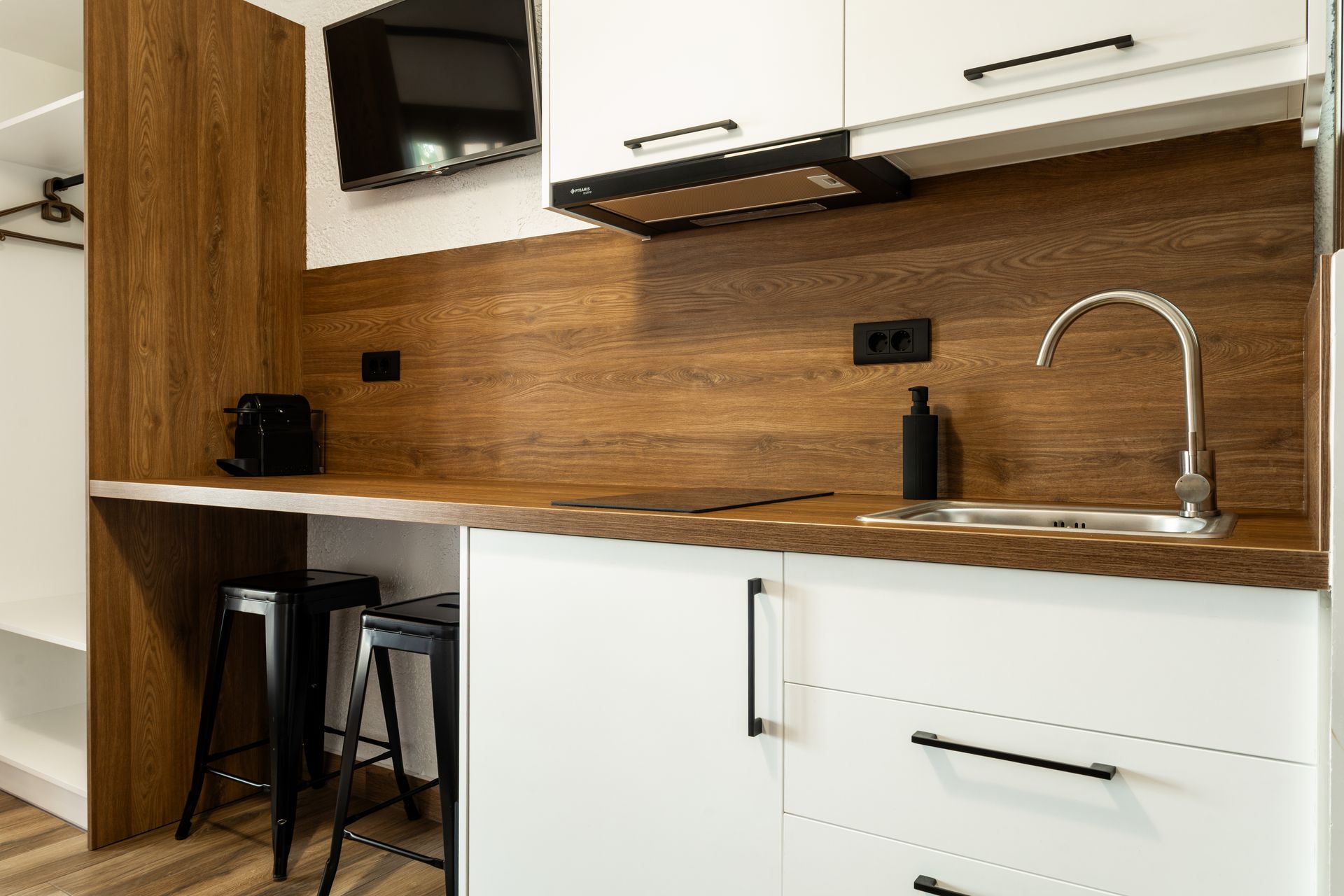 Modern kitchen with wood backsplash, white cabinets, sink, and a small bar seating area