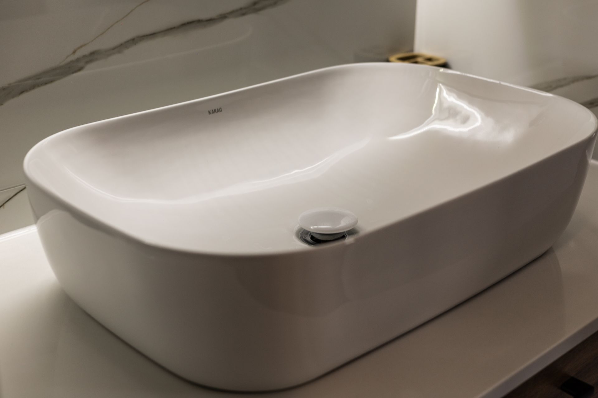 White rectangular bathroom sink with rounded basin and chrome drain on a countertop