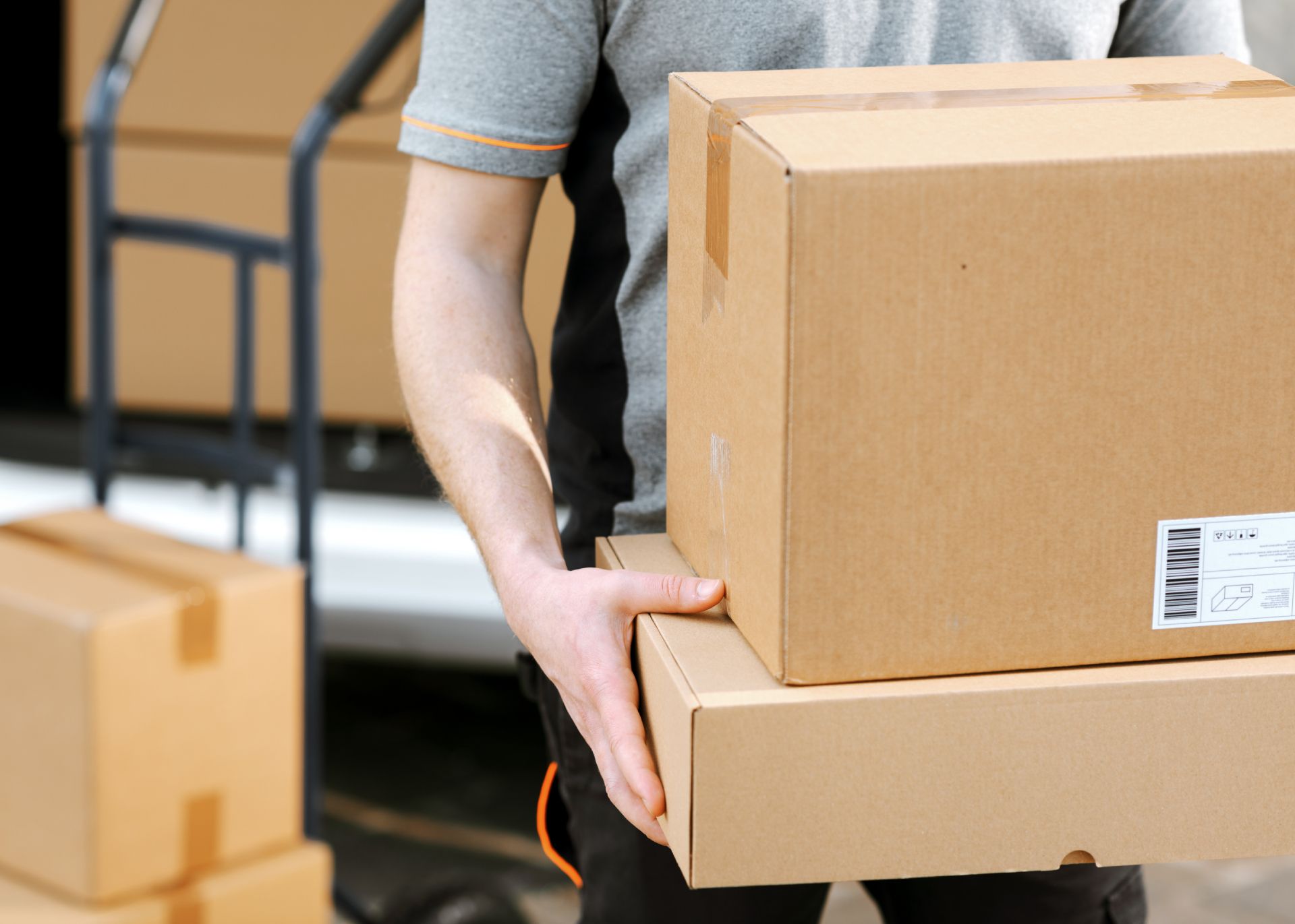 Delivery worker carrying stacked cardboard boxes indoors