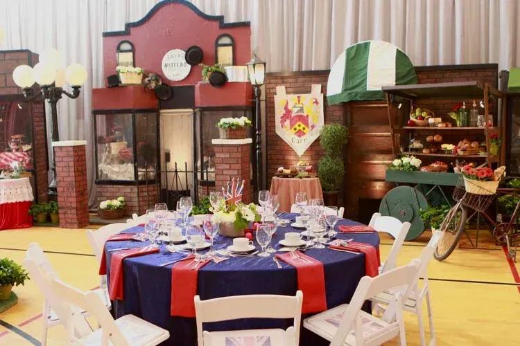 Banquet hall with round table, white chairs, and food displays decorated in red, blue, and green