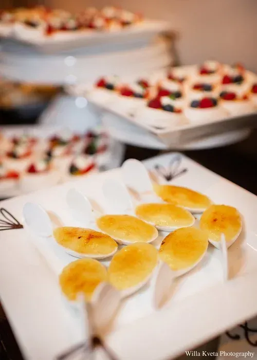 Plates of assorted bite-sized desserts, including glazed pastries and berry-topped treats, arranged on a buffet table