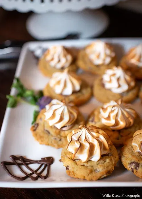 Tray of frosted mini pastries with chocolate drizzle on a white platter