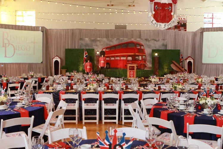 Red and white banquet hall with tables set for an event and a stage at the back
