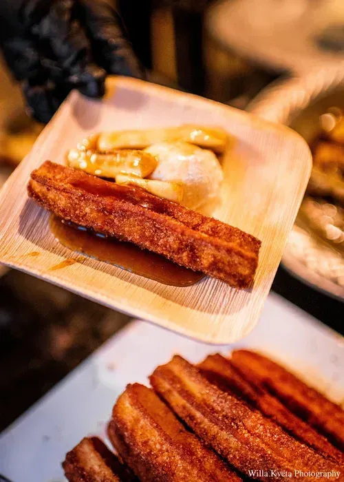 Wooden tray with churros and a scoop of vanilla ice cream on a dessert counter