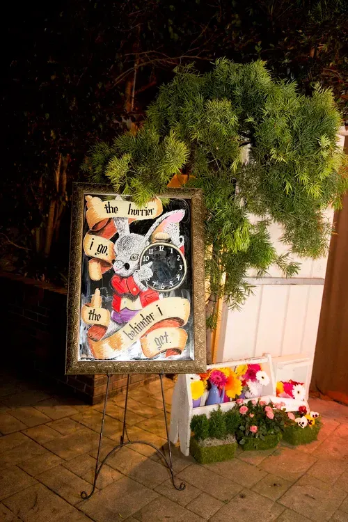 Memorial display with framed artwork, flowers, and greenery on an easel at night
