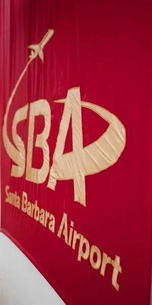 Red Santa Barbara Airport logo on a red wall with a white airplane graphic