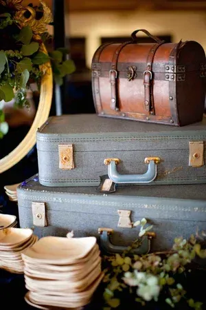 Stacked vintage suitcases with a small brown trunk and decorative flowers in warm, rustic lighting
