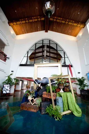 Indoor market display with plants and produce beneath a tall arched ceiling