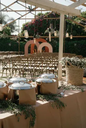 Outdoor wedding reception setup with rows of chairs, round tables, and floral decor under a glass canopy
