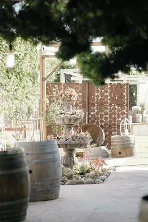 Rustic patio with wooden barrels, potted plants, and a lattice backdrop in soft daylight