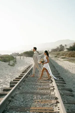 Couple walking on railroad tracks in a bright, scenic outdoor setting