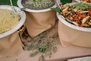 Three large serving bowls of food on a table, including rice, stew, and roasted vegetables.