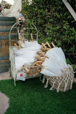 White wicker chair and matching pouf with wooden accents on artificial grass by a leafy wall.